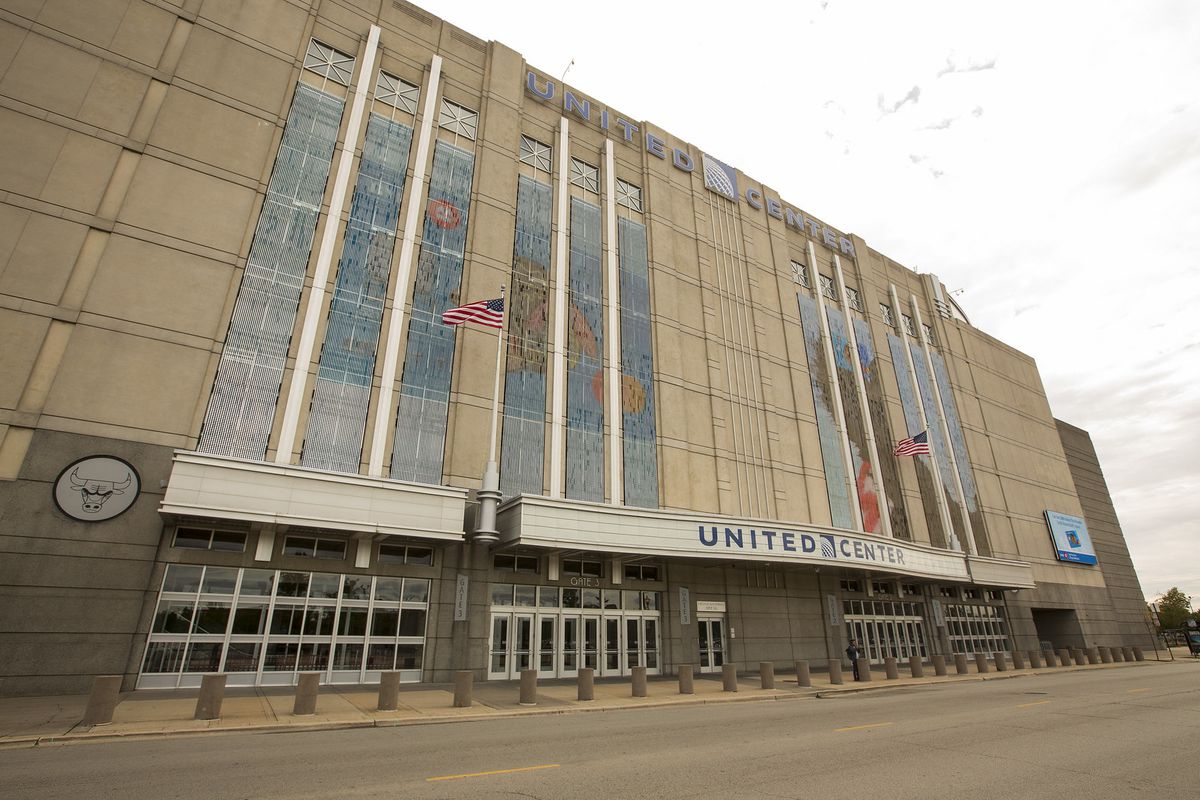 The outside of the sports arena; the United Center with a U.S. flag on a pole waving. It’s dreary outside.