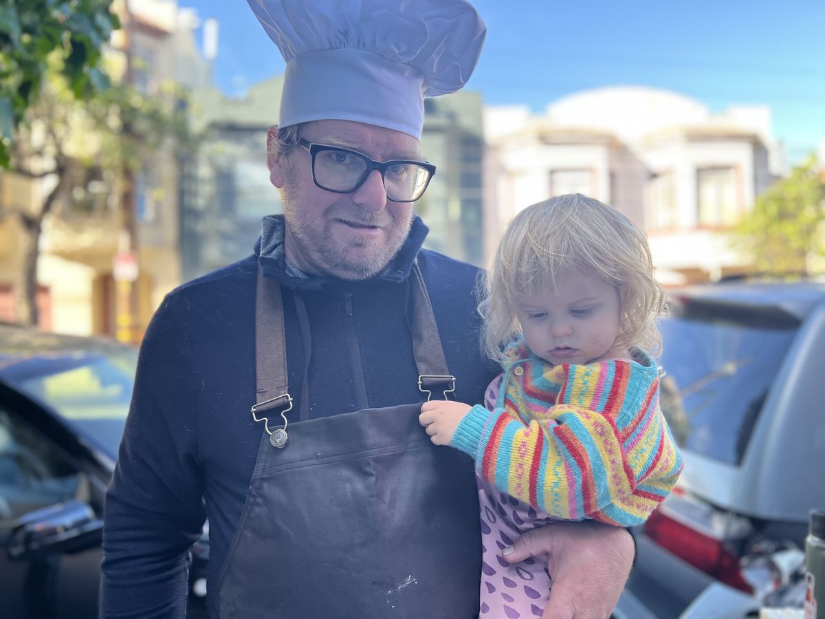 Man holding his daughter in a chef’s toque.