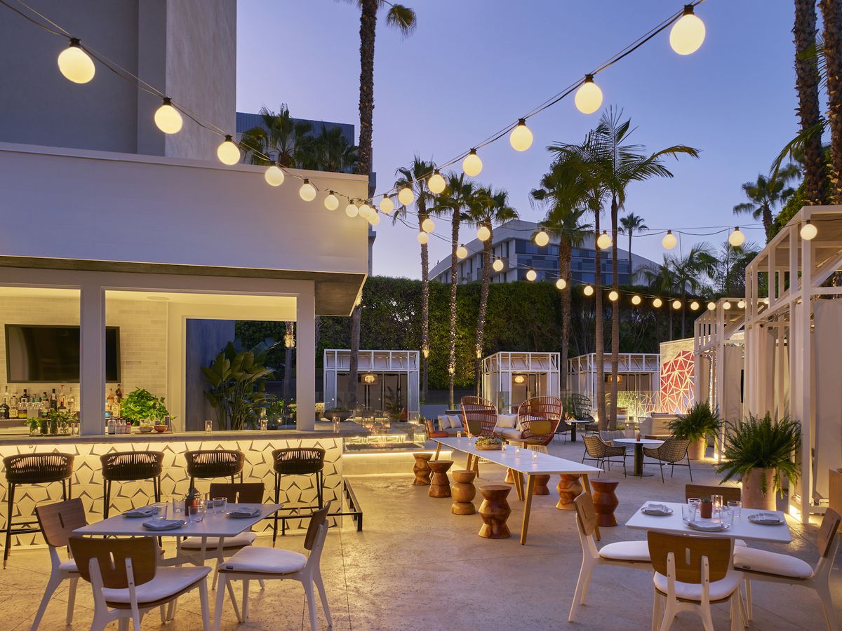 String lights and evening sunset at an outdoor restaurant bar with cabanas.