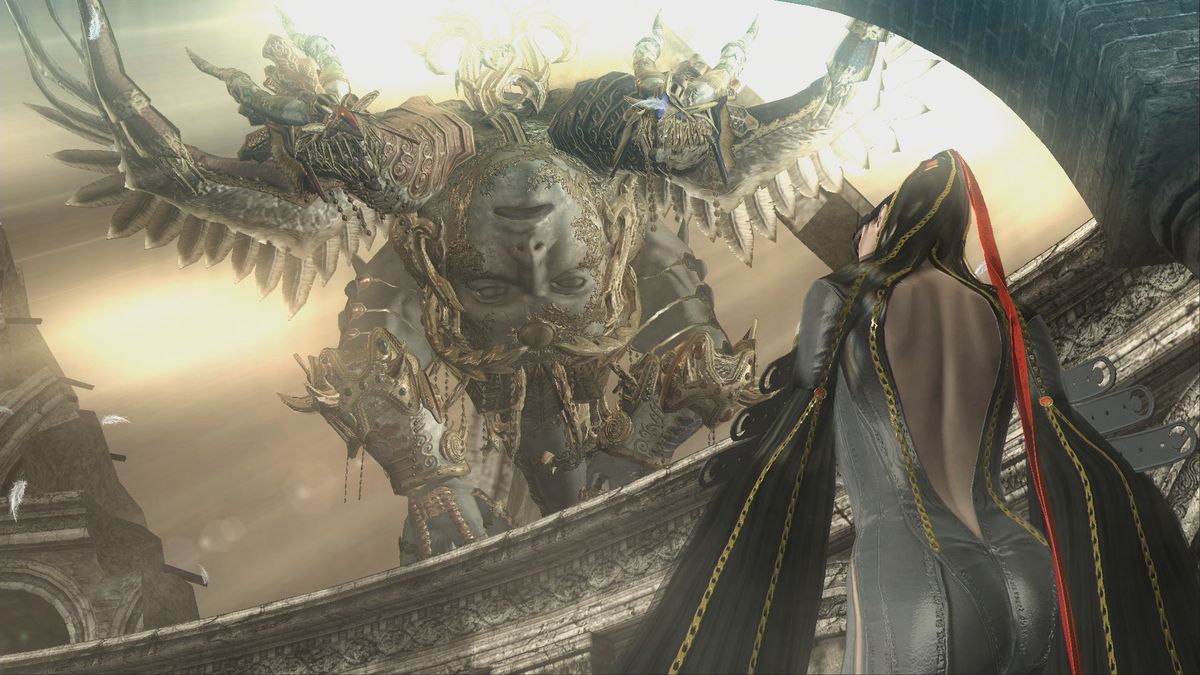 A camera looks up from behind as Bayonetta looks up at a giant monstrous angel in front of her.  The angel is decorated with gold and stone and has an upside down face on it with huge wings.  (It looks like the size of a whole building.) 