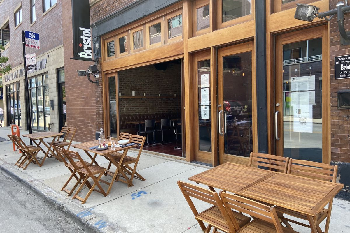 A sidewalk cafe with tables and chairs outside a restaurant.