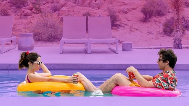 A couple sitting in rubber rings float on the surface of a swimming pool