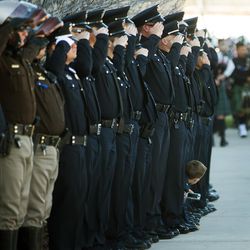 A young boy pokes his head out to get a better view as West Valley police officer Cody Brotherson's casket moves past following funeral services at the Maverik Center in West Valley City on Monday, Nov. 14, 2016.