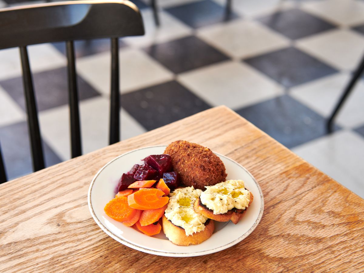 A plate with crostini, pickled carrots and beets, and arancini.