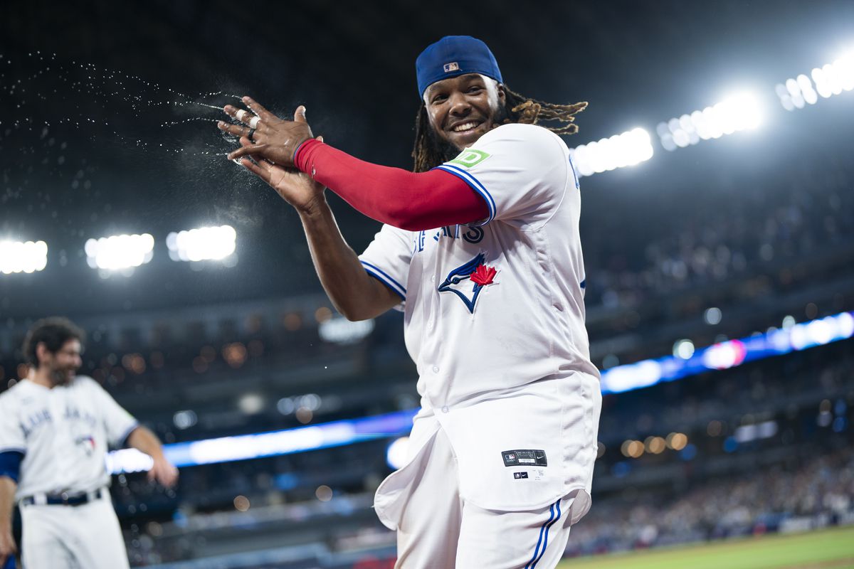 Vladimir Guerrero Jr. #27 of the Toronto Blue Jays smiles after dousing Jordan Romano #68 with water by teammate after their team defeated the Philadelphia Phillies in their MLB game at the Rogers Centre on August 15, 2023 in Toronto, Ontario, Canada.