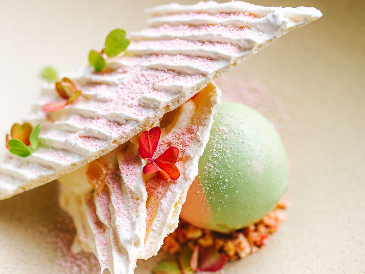 A delicate green and pink mille-feuille dessert in a white dish.