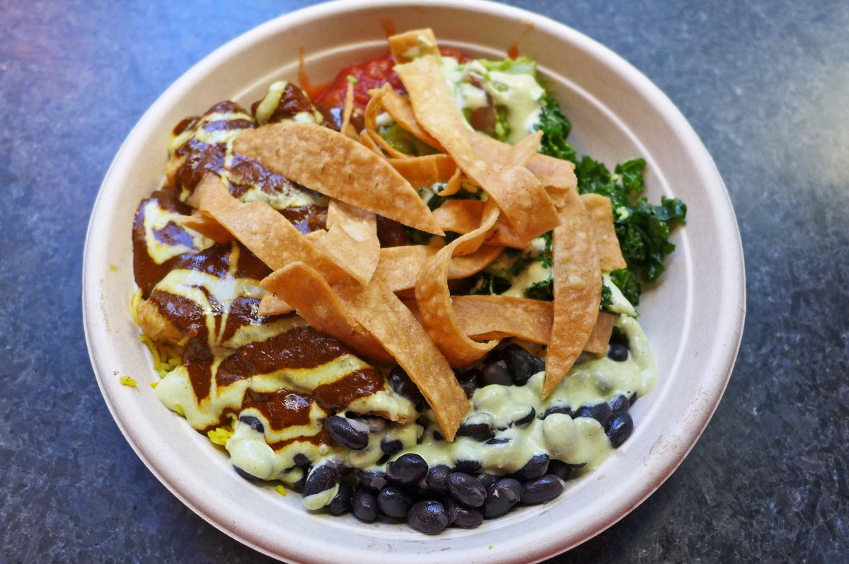 A bowl with tortilla chips on top and black beans visible around the edge.