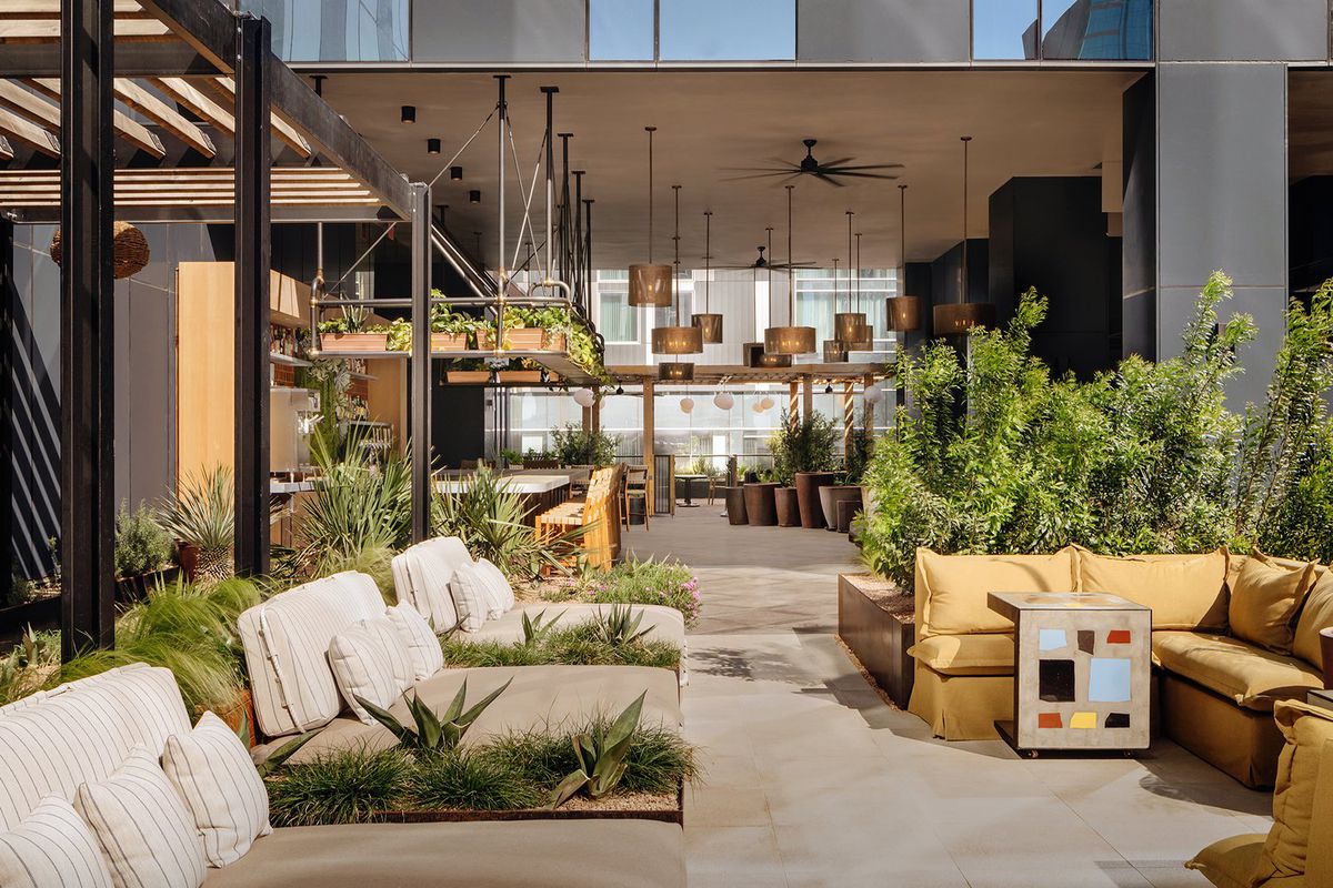 A restaurant patio with lots of plants and lounge furniture.