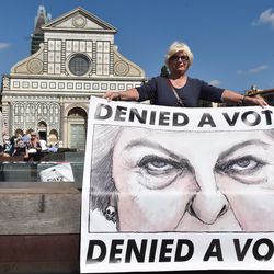 A woman holds a poster showing British Prime Minister Theresa May during a protest staged by a group of UK citizens living in Italy, in Florence, Italy, Friday, Sept. 22, 2017. British Prime Minister Theresa May, who is expected to deliver a speech about Brexit in Florence, will try Friday to revive foundering Brexit talks, and unify her fractious government, by proposing a two-year transition after Britain's departure from the European Union in 2019 during which the U.K. would continue to pay into the bloc's coffers.