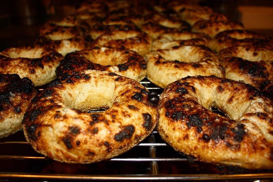 many wood-fired bagels with blackened spots on a baking rack