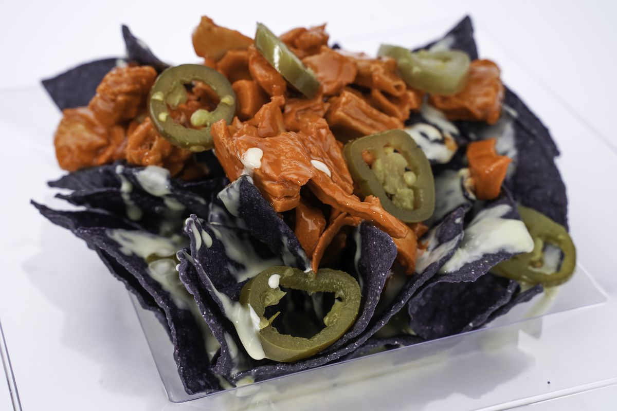 Blue corn tortilla chips topped with cheese, buffalo chicken, and pickled jalapenos
