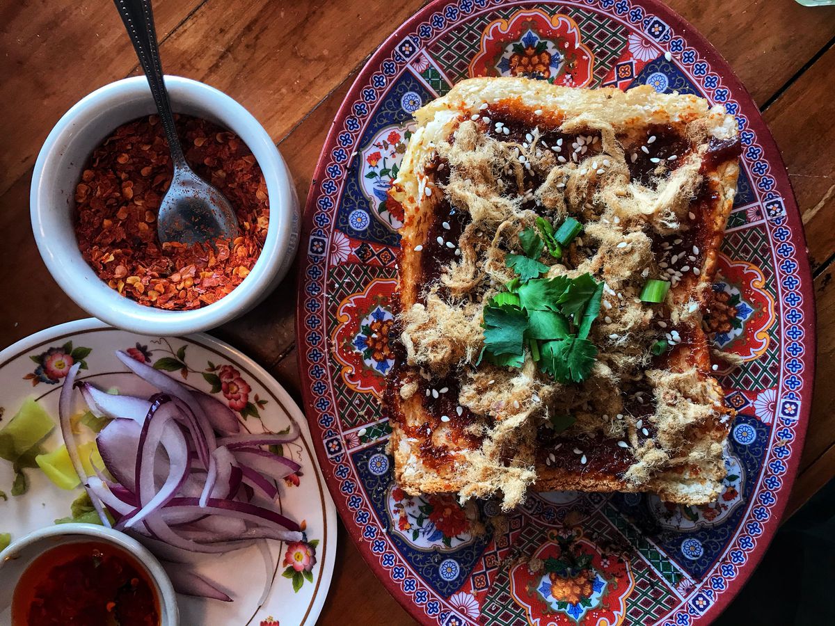 Thai sweet chili paste blankets a piece of bread with cilantro and sesame seeds.