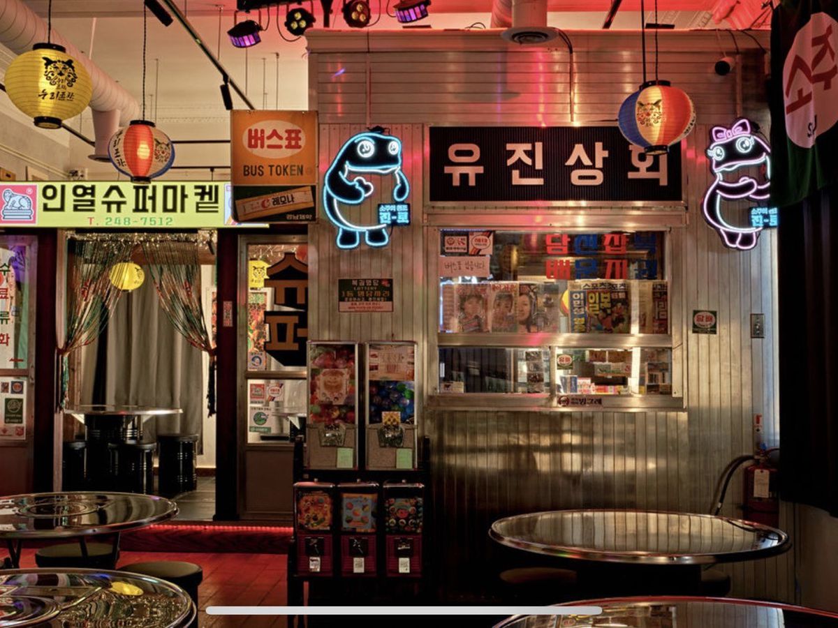 The interior of Noori Pocha/Chicken with neon lighting decor, signs in Korean, a service window, and seating in Clawson, Michigan.