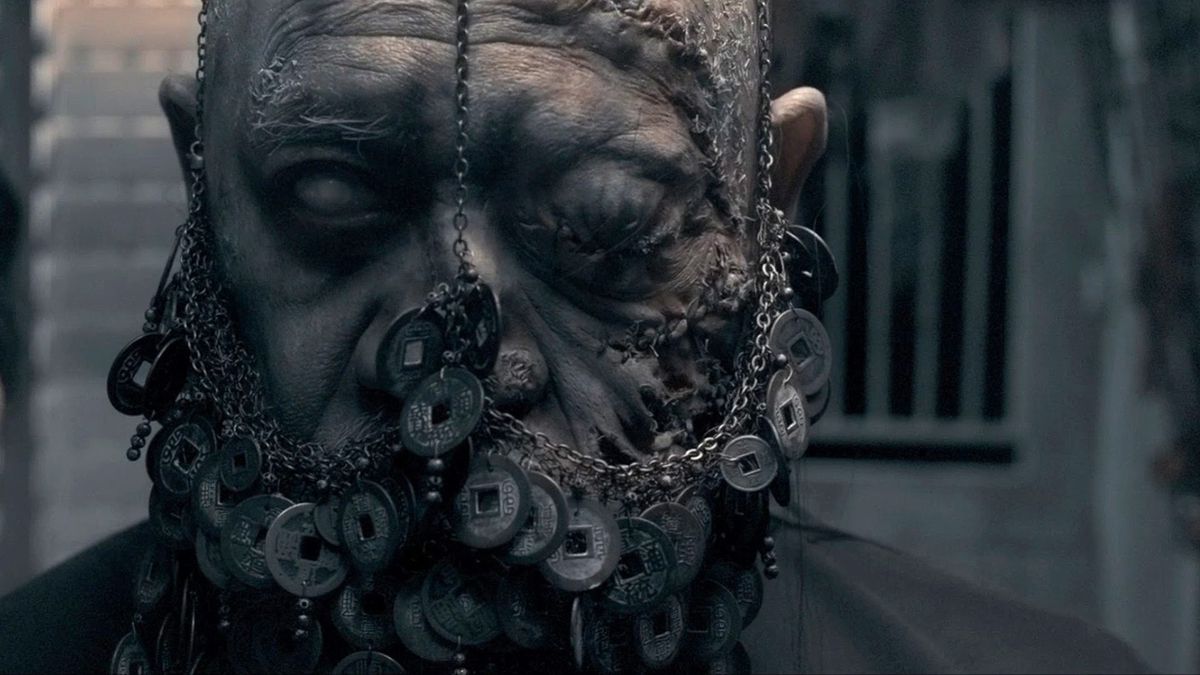 An undead person has coins chained to his face in Rigor Mortis