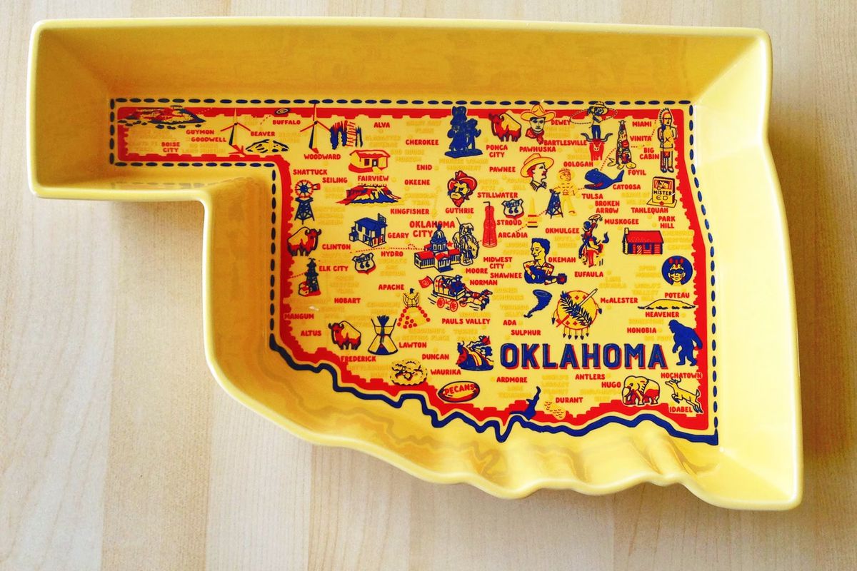 A yellow casserole dish shaped like Oklahoma with small illustrations of state landmarks on the bottom