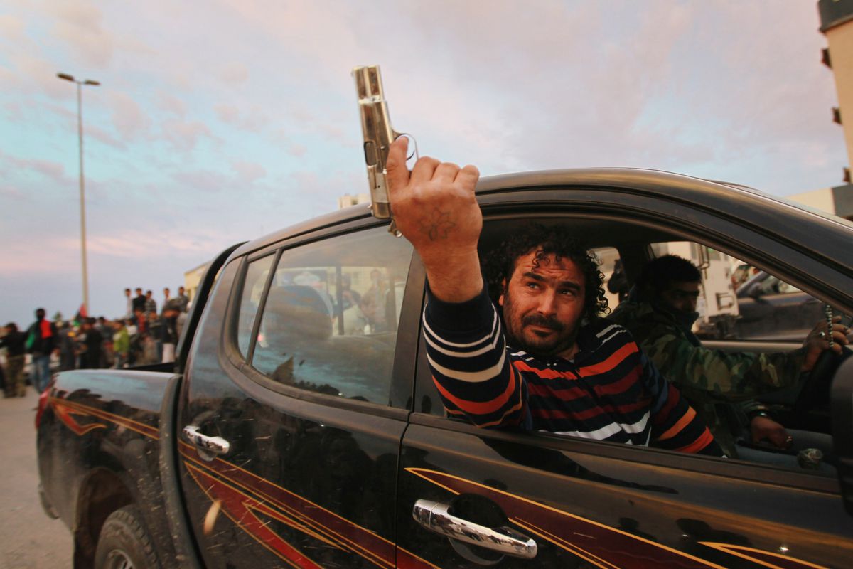 A Libyan man celebrates the initial NATO intervention in March 2011 by firing a pistol in the air.