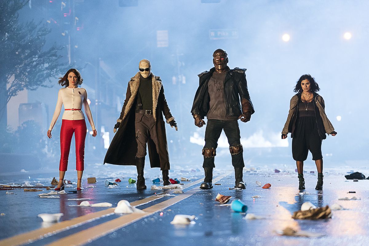 Elastigirl, Negative Man, Robotman, and Crazy Jane stand abreast on a trash-strewn city street in Doom Patrol.