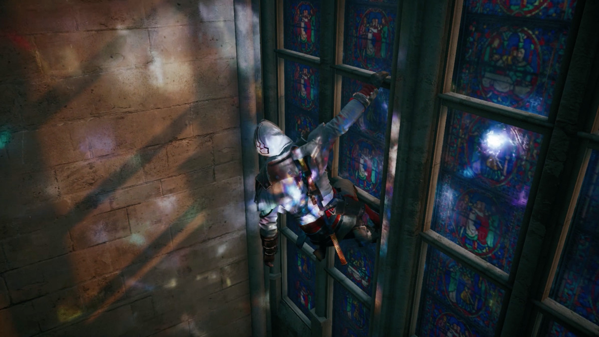 An image of Arno hanging from a stained glass window inside Notre-Dame in Assassin’s Creed Unity; the light falls on him and the stone wall in blue and red splotches