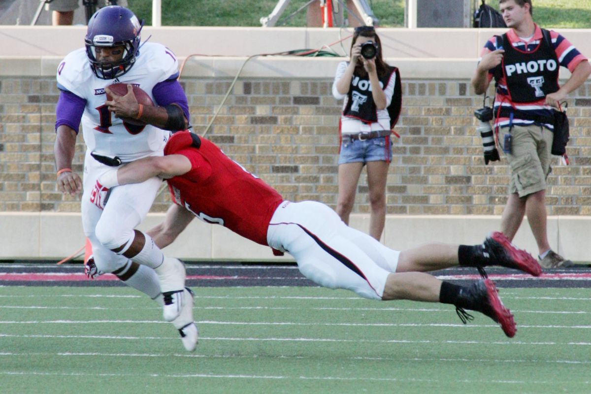Sept 1, 2012; Lubbock, TX, USA; Northwestern State Demons quarterback Brad Henderson (10) is tackled by Texas Tech Red Raiders safety Cody Davis (16) in the first half at Jones AT&T Stadium. Mandatory Credit: Michael C. Johnson-US PRESSWIRE