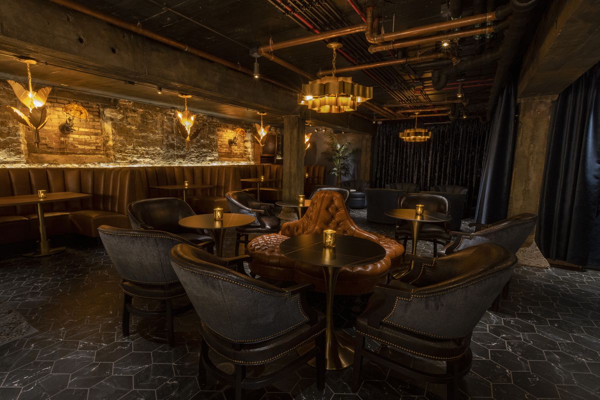 A low-lit speakeasy-style bar filled with leather furniture. 
