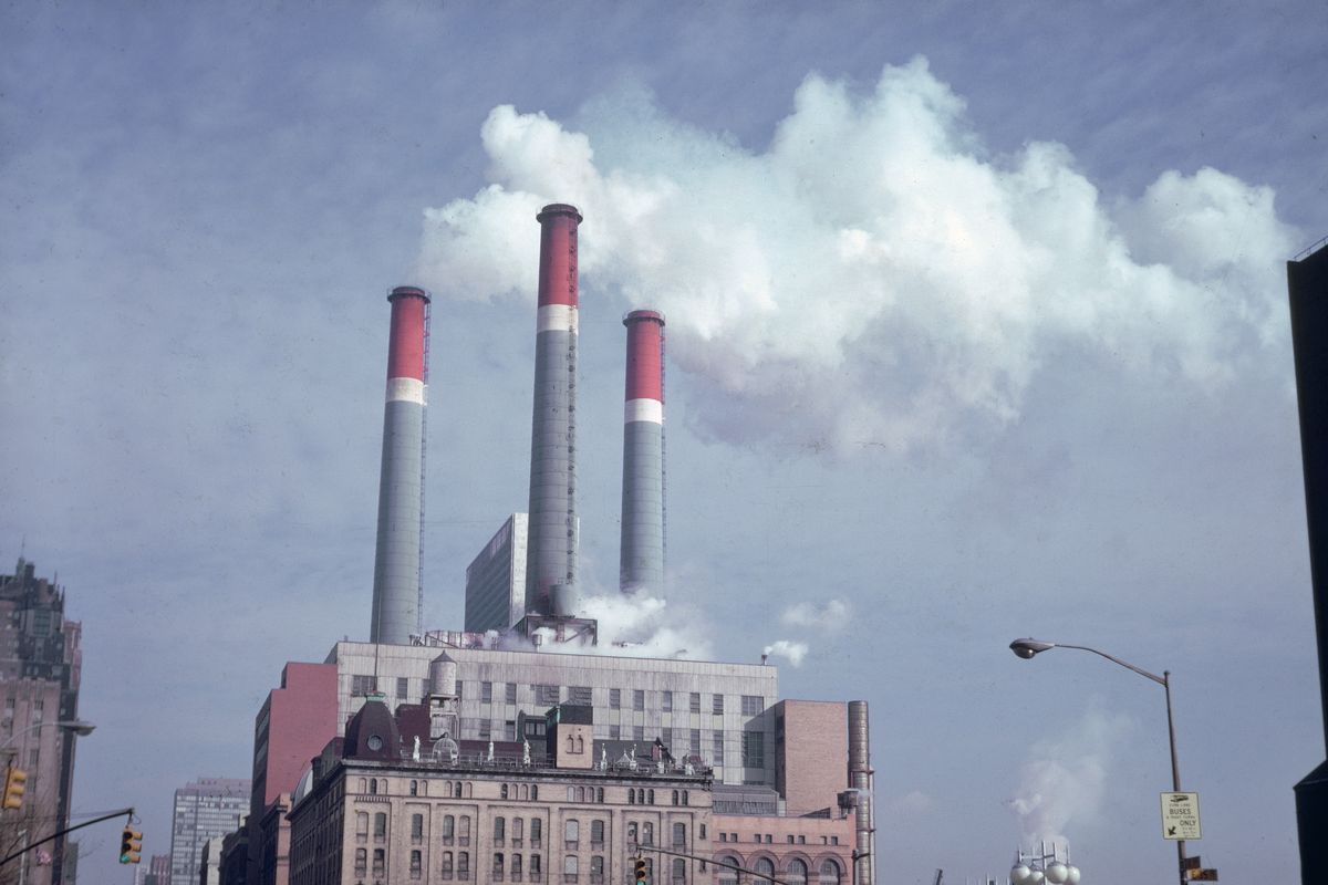 Smokestacks emitting smoke at an industrial building, 1970s. 