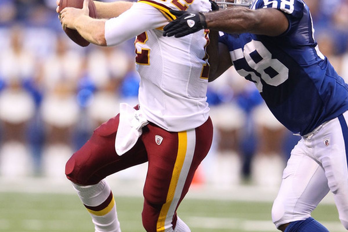 INDIANAPOLIS, IN - AUGUST 19:  John Beck #12 of the Washington Redskins is tackled by Gary Brackett #58 of the Indianapolis Colts during the game at Lucas Oil Stadium on August 19, 2011 in Indianapolis, Indiana.  (Photo by Andy Lyons/Getty Images)