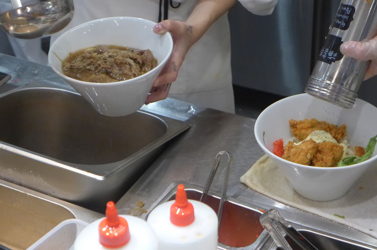 Two bowls are being tended too, one with beef the other with fried chicken.
