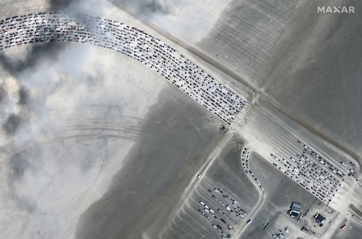 Aerial shot of the Nevada desert with a ten-lane winding row of cars waiting to get into the festival. 