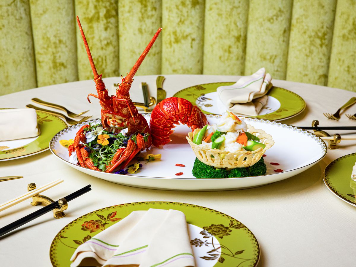 A plate of whole lobster, artfully arranged with vegetables.