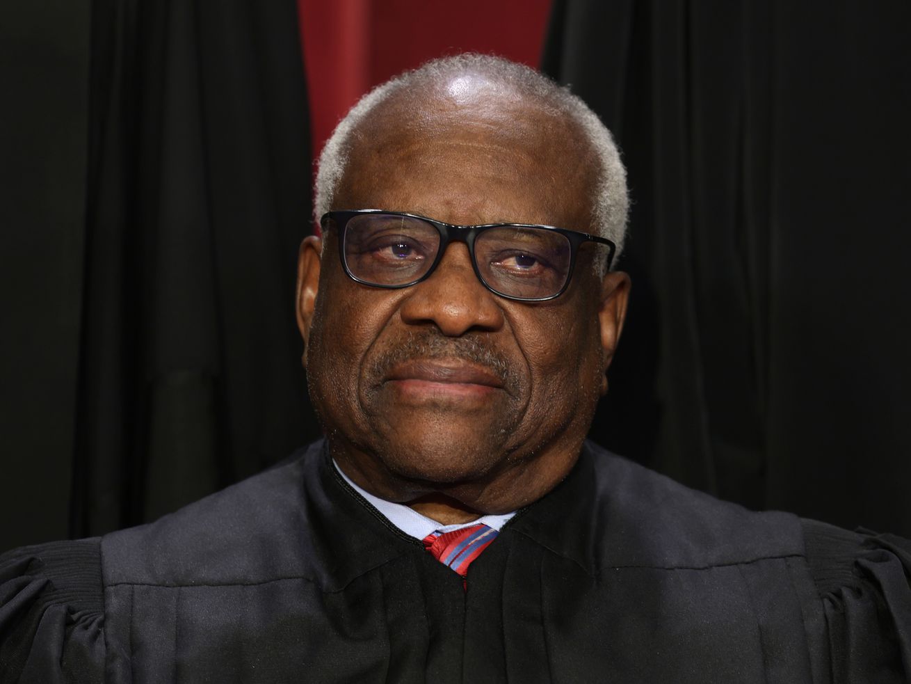 Justice Clarence Thomas in black robes, staring ahead.