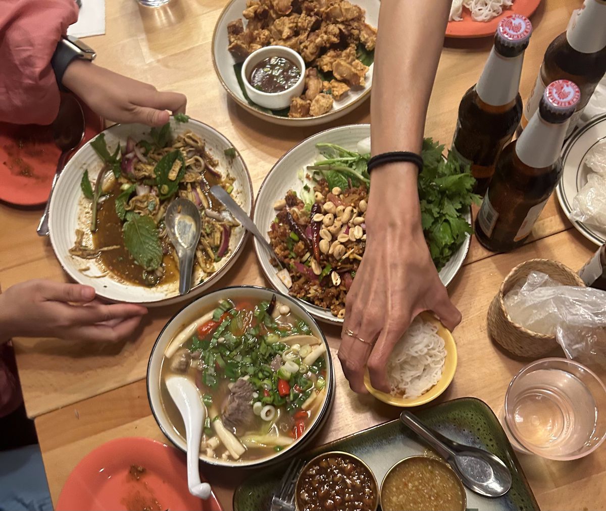An overhead photograph of a table of soups, salads, and rice dishes at Hug Esan, a Thai restaurant in Queens.