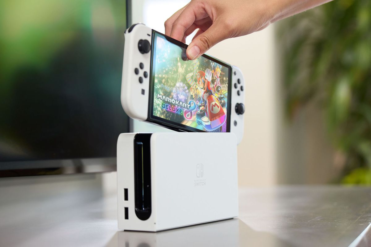 A Nintendo Switch OLED Model being inserted into its dock