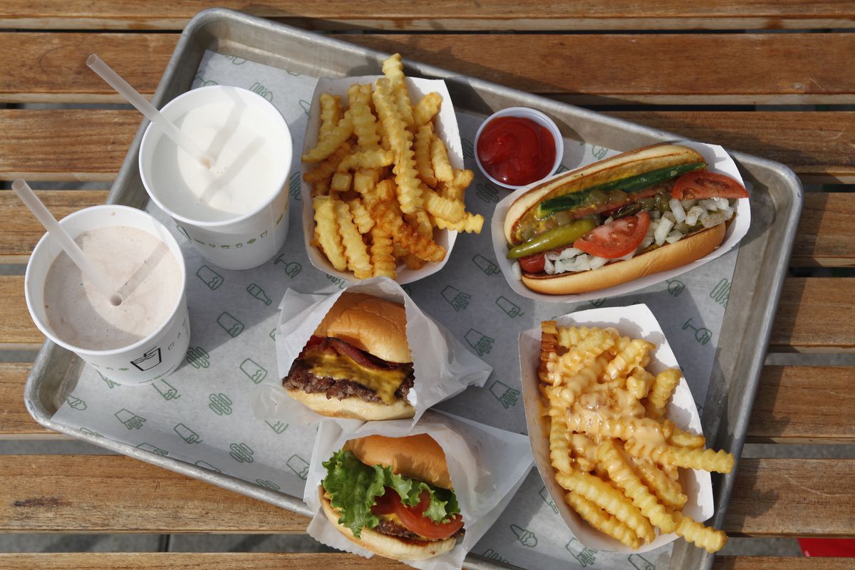An overhead photograph of a cafeteria tray with burgers, fries, and shakes.