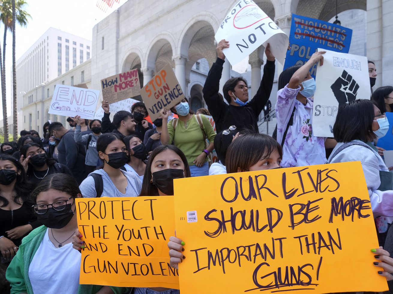 A crowd of students on the steps outside a government building hold signs that read “Our lives should be more important than guns!” and “Protect the youth and end gun violence.”
