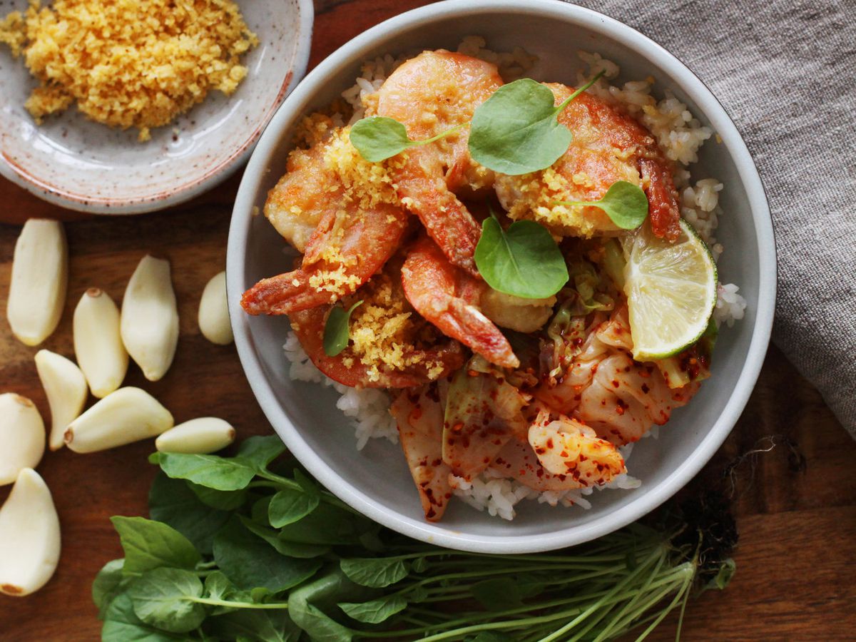 From above, a bowl of garlic shrimp over rice, staged with ingredients nearby.