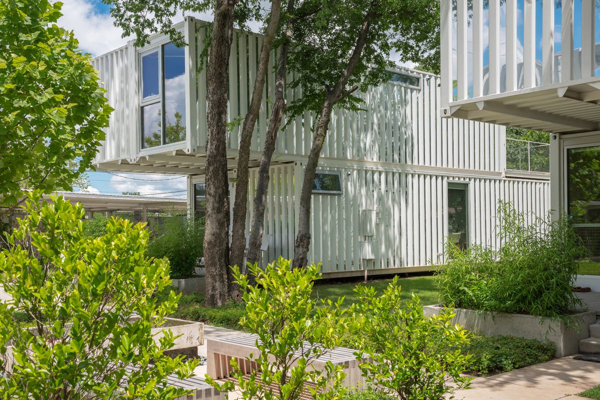 Homes built from white shipping containers surrounded by trees. 