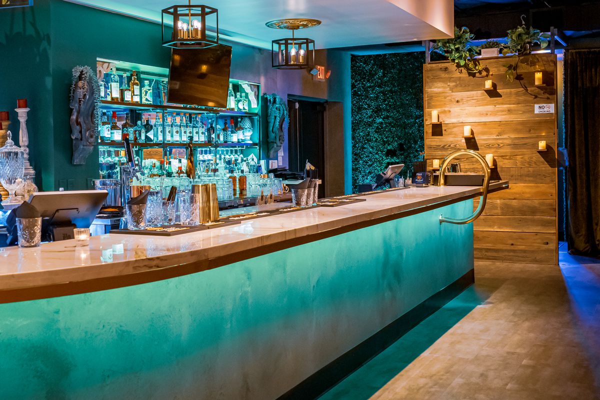 A pretty teal bar with a wood wall on the right.