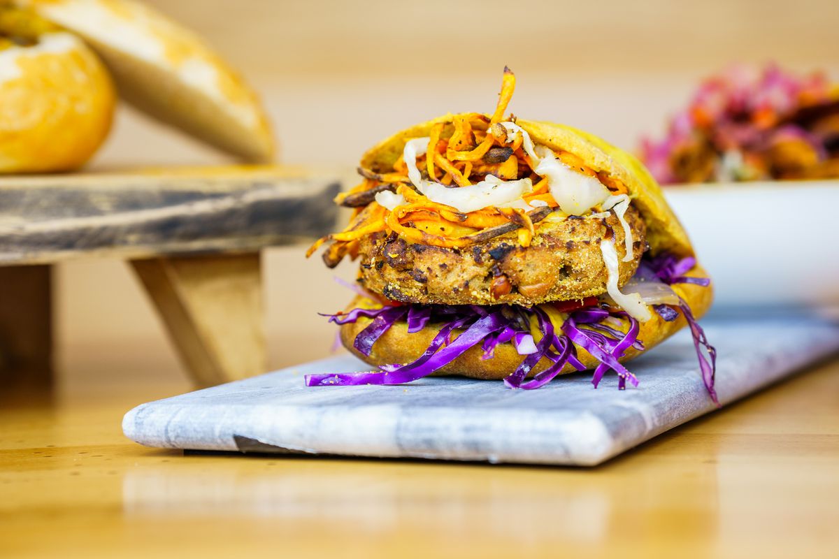 A sandwich with a fritter and bright purple cabbage shavings stuffed into a pita pocket.