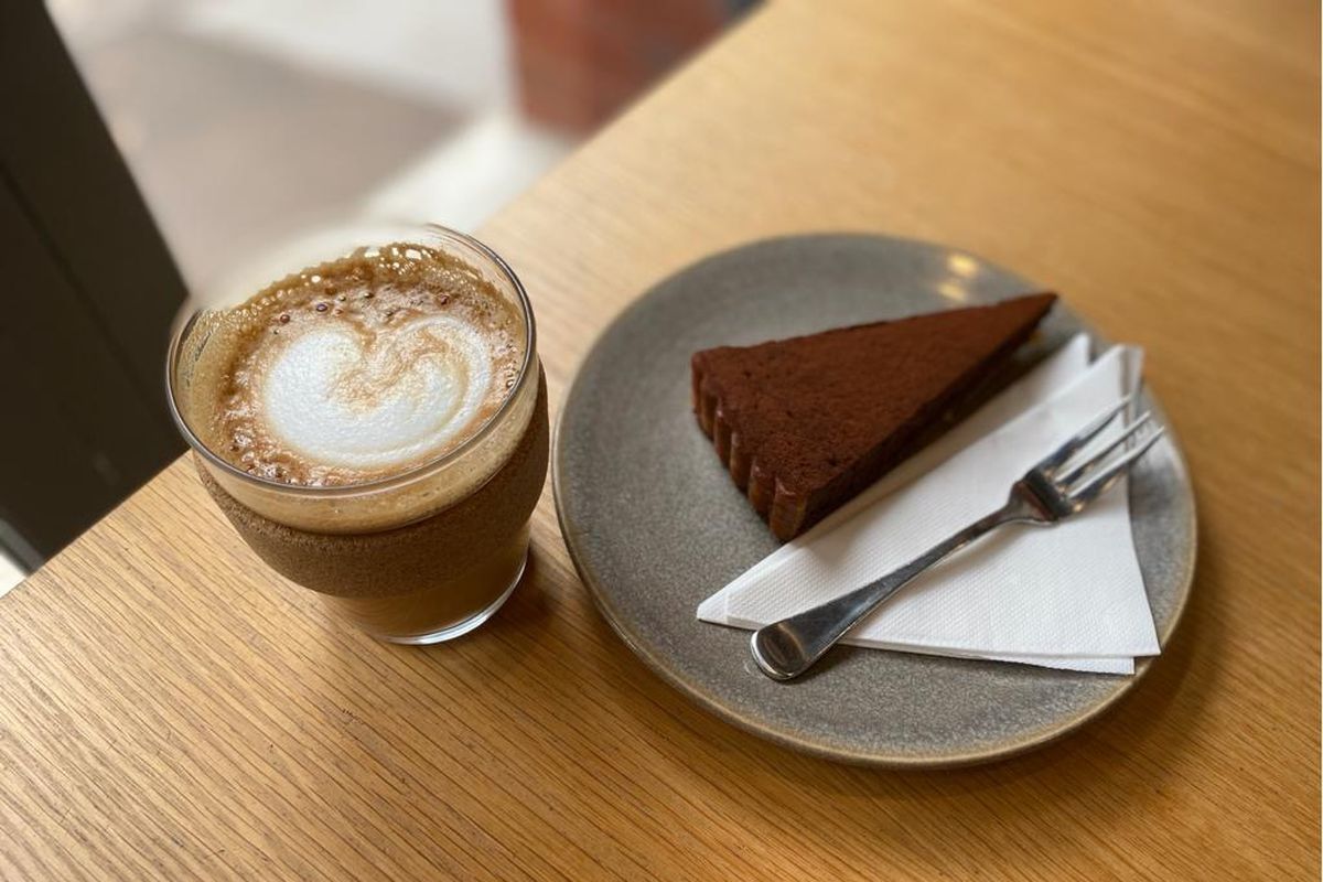 Coffee and a slice of chocolate tart on a gray plate with a fork.