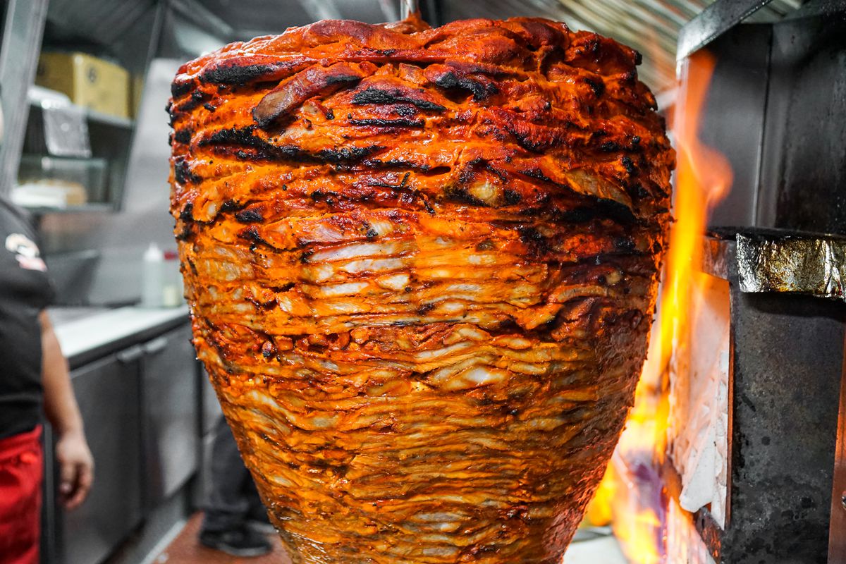 Close up of grilling pork on a revolving spit.