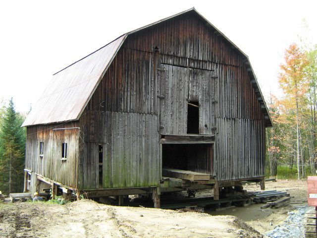 Old, decaying barn in front of a muddy, construction-like area. 