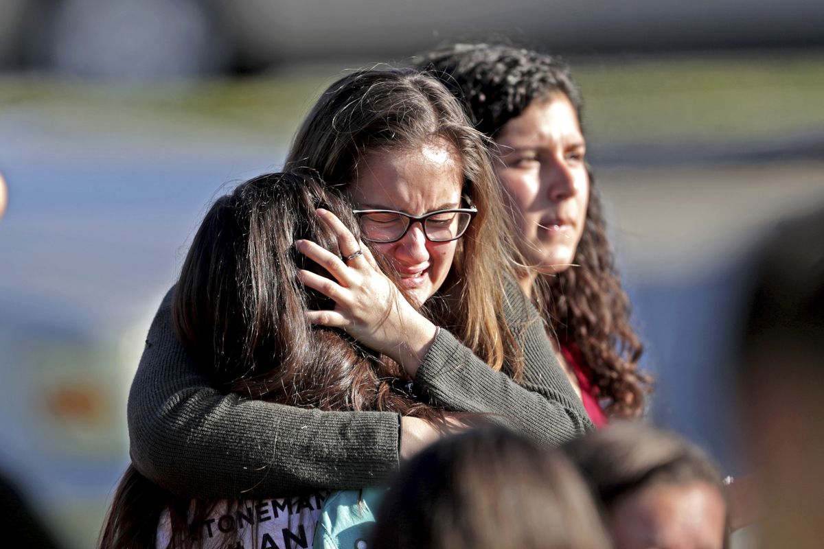 Students released from a lockdown embrace following following a shooting at Marjory Stoneman Douglas High School in Parkland, Fla., Wednesday, Feb. 14, 2018. (John McCall/South Florida Sun-Sentinel via AP)