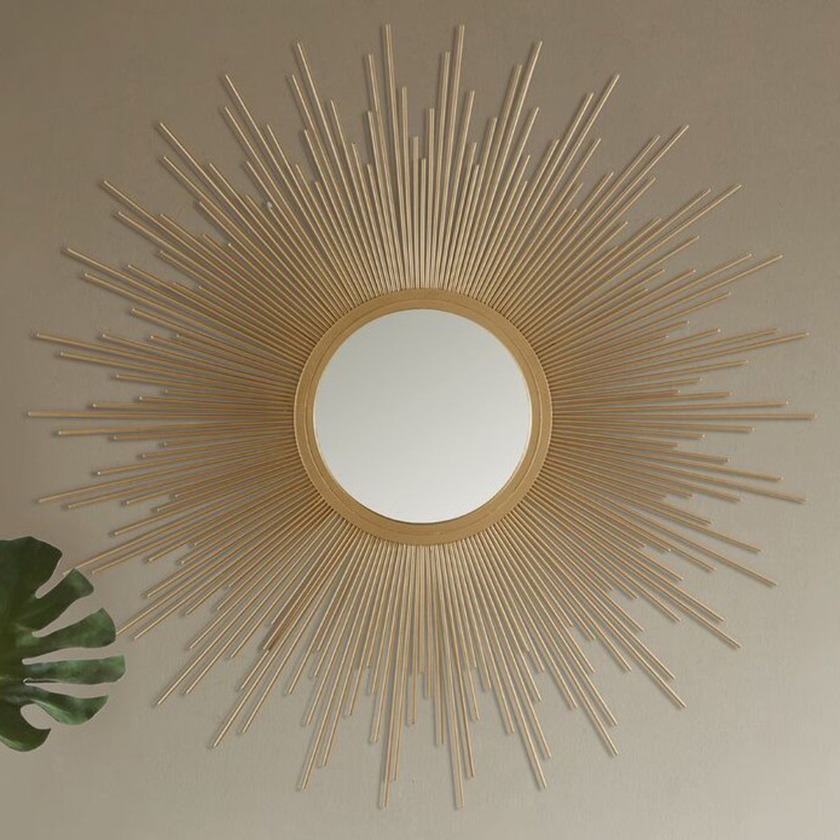 A golden round mirror with stick-shaped pieces radiating from the center like the sun’s rays. 