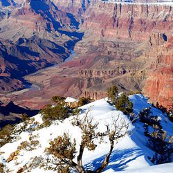 Snow covers a rocky promontory below the Deseret View observation tower at the east entrance to Grand Canyon National Park, the Colorado River flowing far below.