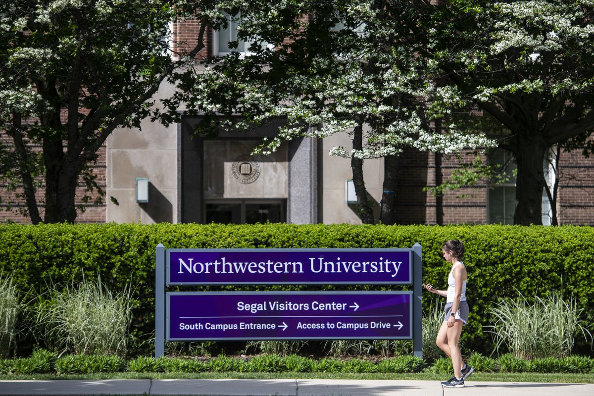 A woman walks by a Northwestern University sign near Sheridan Road