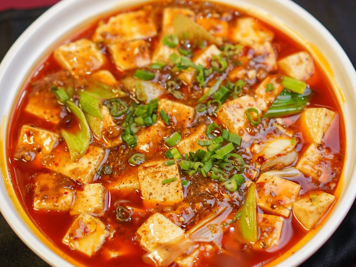 Soft tofu cubes float in a pool of chili oil in a bowl.