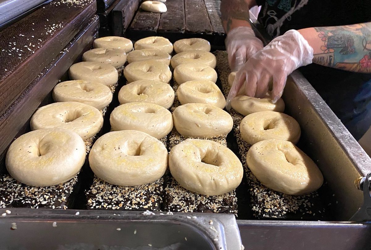 A pair of hands in gloves handling bagels before cooking.
