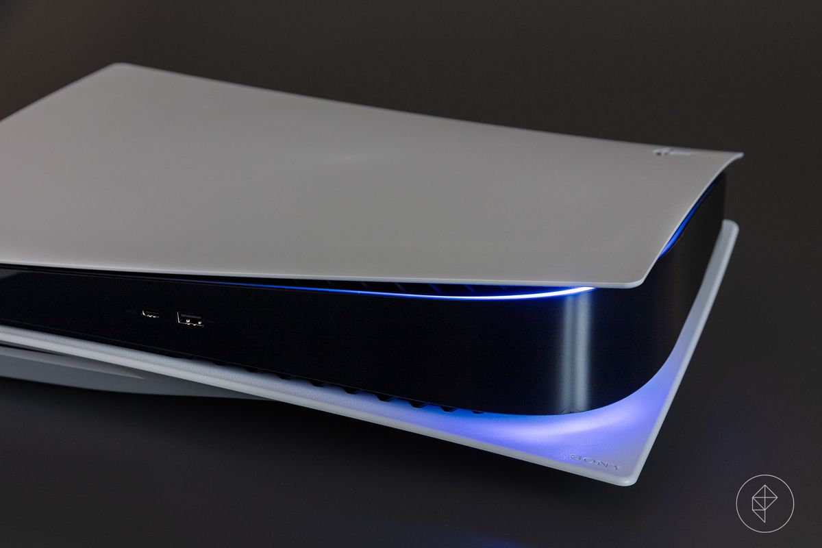The PlayStation 5 laying on its side, turned on, showing a blue light at its edges