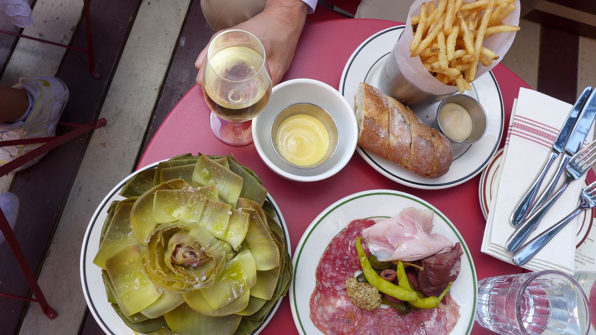 An artichoke, french fries, and charcuterie plate, seen from above.