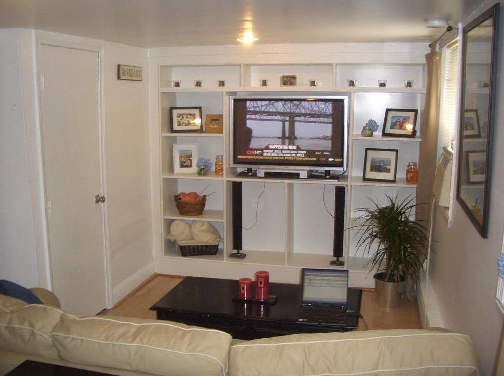 A living room with a couch facing built-in shelves with a TV.